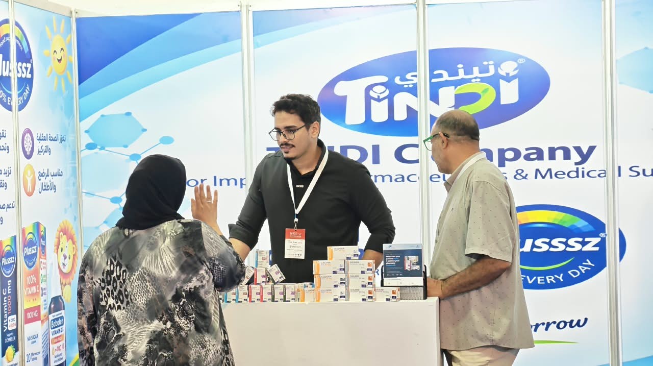 Un membre de l'équipe TINDI échange avec deux visiteurs sur le stand